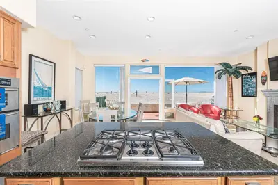 a kitchen with a stove top in a room with a beach at Affordable 2Br Oceanfront W Large Patio, Boardwalk Access By Beachview Rentals in Newport Beach