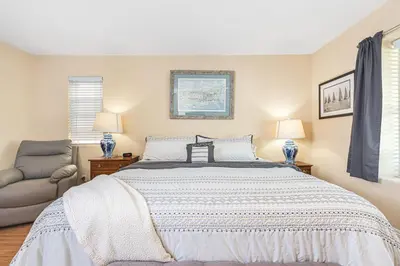 a bedroom with a bed and a chair at Affordable 2Br Oceanfront W Large Patio, Boardwalk Access By Beachview Rentals in Newport Beach