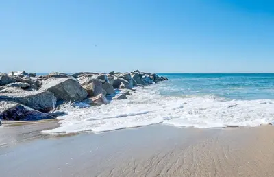 a beach with rocks and the ocean on a sunny day at 3Br W Oceanview Patio, 1 House From Popular 40Th St Beach By Beachview Rentals in Newport Beach