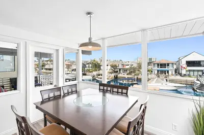 a dining room with a table and chairs and a large window at Stylish 3Br Bayfront Home W Balcony And Waterfront Views By Beachview Rentals in Newport Beach