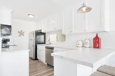 a white kitchen with white cabinets and a refrigerator at Stylish 3Br Bayfront Home W Balcony And Waterfront Views By Beachview Rentals in Newport Beach