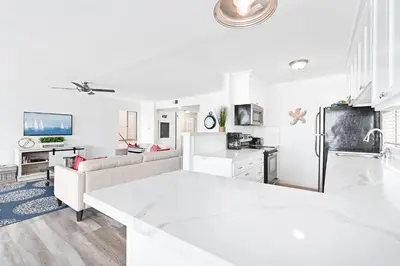 a white kitchen and living room with a couch and a refrigerator at Stylish 3Br Bayfront Home W Balcony And Waterfront Views By Beachview Rentals in Newport Beach