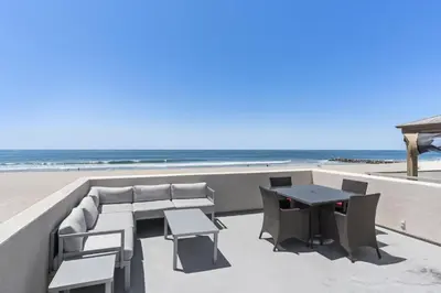 a patio with a table and chairs and the beach at Modern 3Br Oceanfront W Rooftop Deck And Panoramic Views By Beachview Rentals in Newport Beach