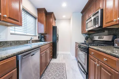 a kitchen with wooden cabinets and a black refrigerator at Updated 3Br W Oceanview Rooftop Deck, Steps To The Beach By Beachview Rentals in Newport Beach