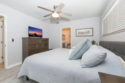a bedroom with a white bed with a ceiling fan at Updated 3Br W Oceanview Rooftop Deck, Steps To The Beach By Beachview Rentals in Newport Beach