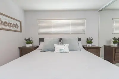 a white bed with two pillows on it in a bedroom at Updated 3Br W Oceanview Rooftop Deck, Steps To The Beach By Beachview Rentals in Newport Beach