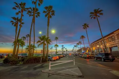 a street with cars parked in a parking lot with palm trees at Updated 3Br W Oceanview Rooftop Deck, Steps To The Beach By Beachview Rentals in Newport Beach