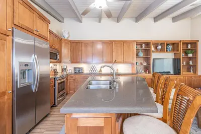 a kitchen with wooden cabinets and a stainless steel refrigerator at Charming 2Br Condo W Ac, Steps To Beach And Balboa Pier By Beachview Rentals in Newport Beach