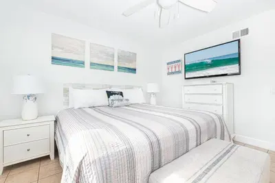 a white bedroom with a bed and a flat screen tv at Spacious 4Br W Ocean Views And 2 Balconies, Steps To Sand By Beachview Rentals in Newport Beach