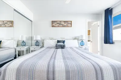 a bedroom with a large bed with a striped comforter at Spacious 4Br W Ocean Views And 2 Balconies, Steps To Sand By Beachview Rentals in Newport Beach