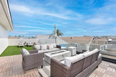 a patio with wicker chairs and tables on a balcony at Modern 4Br Tri-Level W Rooftop Deck, Ac, Steps From Sand By Beachview Rentals in Newport Beach