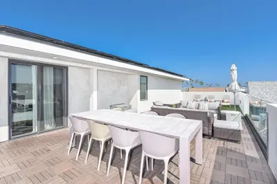 a patio with a white table and chairs on a balcony at Modern 4Br Tri-Level W Rooftop Deck, Ac, Steps From Sand By Beachview Rentals in Newport Beach
