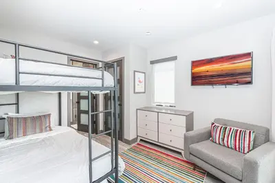 a bedroom with a bunk bed and a couch at Modern 4Br Tri-Level W Rooftop Deck, Ac, Steps From Sand By Beachview Rentals in Newport Beach