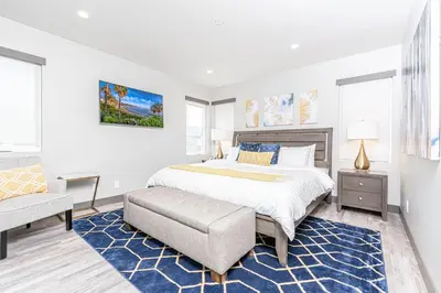 a white bedroom with a bed and a chair at Modern 4Br Tri-Level W Rooftop Deck, Ac, Steps From Sand By Beachview Rentals in Newport Beach