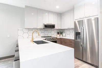 a kitchen with white cabinets and a stainless steel refrigerator at Modern 4Br Tri-Level W Rooftop Deck, Ac, Steps From Sand By Beachview Rentals in Newport Beach