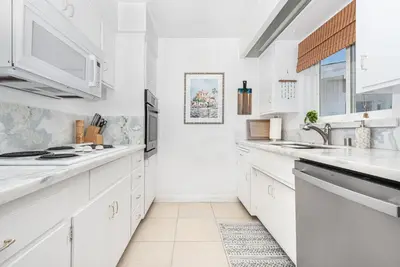 a white kitchen with white cabinets and a sink at Affordable 2Br, Central Location, Walk To Beach And Dining By Beachview Rentals in Newport Beach