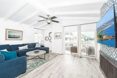 a living room with a blue couch and a tv at Remodeled 7Br Duplex Near Beach, Shops, And Dining By Beachview Rentals in Newport Beach