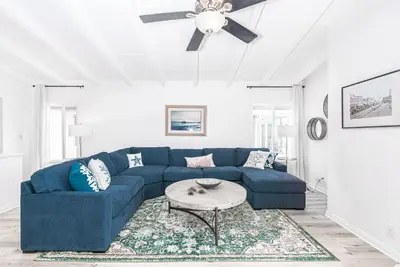 a blue couch in a living room with a ceiling fan at Remodeled 7Br Duplex Near Beach, Shops, And Dining By Beachview Rentals in Newport Beach