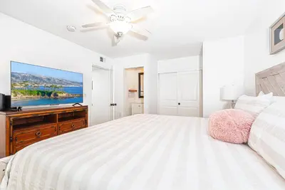 a white bedroom with a bed and a flat screen tv at Remodeled 7Br Duplex Near Beach, Shops, And Dining By Beachview Rentals in Newport Beach