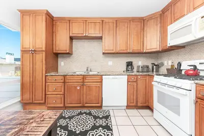 a kitchen with wooden cabinets and white appliances at Spacious 5Br W Oceanview Balcony - One House From Beach By Beachview Rentals in Newport Beach