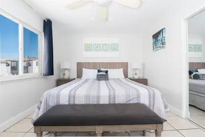 a white bedroom with a bed and two windows at Spacious 5Br W Oceanview Balcony - One House From Beach By Beachview Rentals in Newport Beach