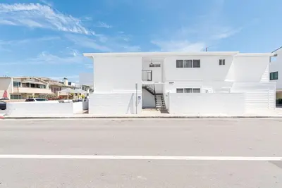a white house on the side of a street at Spacious 5Br W Oceanview Balcony - One House From Beach By Beachview Rentals in Newport Beach