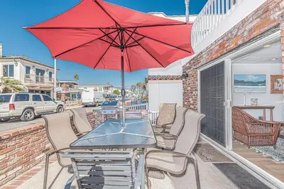 a table and chairs with a red umbrella on a patio at 7Br Duplex W Oceanview Balcony And Ac, Walk To It All By Beachview Rentals in Newport Beach