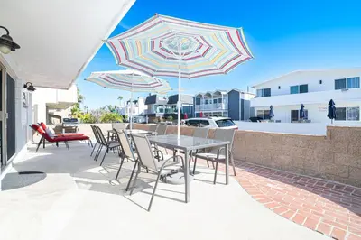 a table and chairs with umbrellas on a patio at 3Br W Spacious Oceanview Patio, Only One House From Sand By Beachview Rentals in Newport Beach