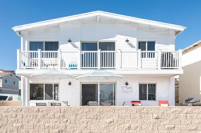 a white house with chairs and umbrellas in front of it at 3Br W Spacious Oceanview Patio, Only One House From Sand By Beachview Rentals in Newport Beach