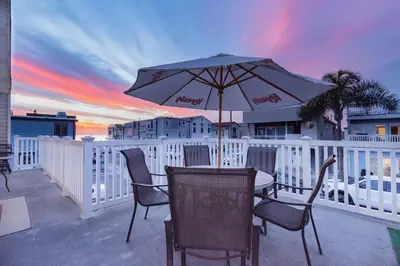 a table and chairs with an umbrella on a balcony at Spacious 4Br W Oceanview Balcony And Bbq, Steps To Sand By Beachview Rentals in Newport Beach