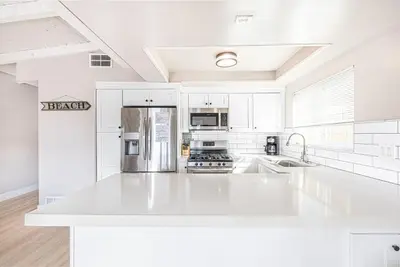 a white kitchen with a large white counter top at Stylish 6Br Duplex, One Block From Beach And Boardwalk By Beachview Rentals in Newport Beach