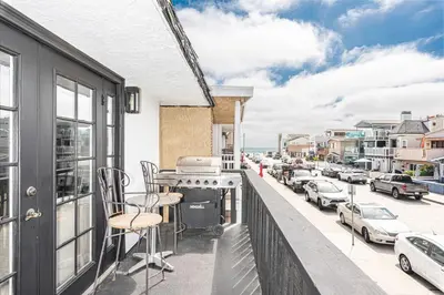 a balcony with a grill and chairs on a city street at Stylish 6Br Duplex, One Block From Beach And Boardwalk By Beachview Rentals in Newport Beach