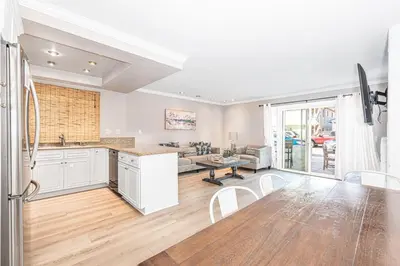 an open kitchen and living room with white cabinets at Stylish 6Br Duplex, One Block From Beach And Boardwalk By Beachview Rentals in Newport Beach