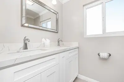 a white bathroom with two sinks and a mirror at Stylish 6Br Duplex, One Block From Beach And Boardwalk By Beachview Rentals in Newport Beach