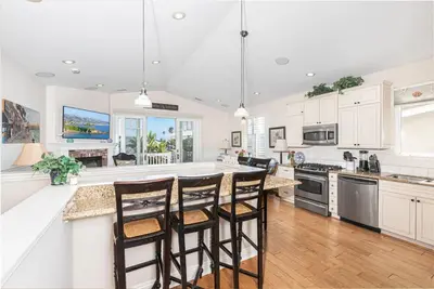 a kitchen with white cabinets and a island with bar stools at Darling 3Br Beach Home On Quiet Street, Easy Walk To Beach By Beachview Rentals in Newport Beach
