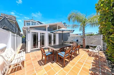 a patio with a table and chairs on a brick patio at Charming 4Br W Large Garden Patio, 2 Houses From The Sand By Beachview Rentals in Newport Beach