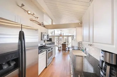 a large kitchen with white cabinets and a stainless steel refrigerator at Charming 4Br W Large Garden Patio, 2 Houses From The Sand By Beachview Rentals in Newport Beach