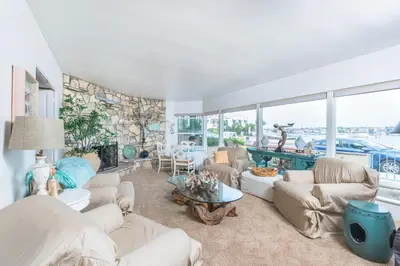 a living room with white furniture and a stone wall at Spacious 3Br Bayfront W Harbor Views, Walk To Beach By Beachview Rentals in Newport Beach