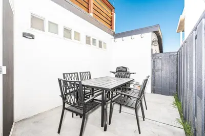 a wooden table and chairs on a patio at Luxury 6Br Triplex In Prime Location One House From Sand By Beachview Rentals in Newport Beach