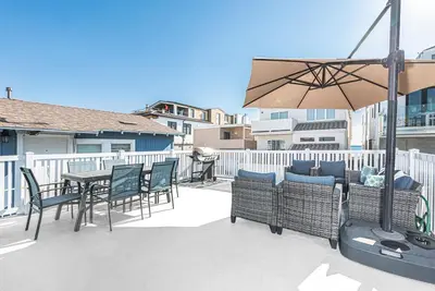 a patio with a table and chairs and an umbrella at Charming 3Br W Large Deck, Walk To Beach And Marina Park By Beachview Rentals in Newport Beach