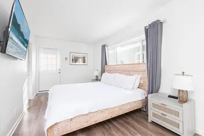 a white bedroom with a large bed and a window at Charming 3Br W Large Deck, Walk To Beach And Marina Park By Beachview Rentals in Newport Beach