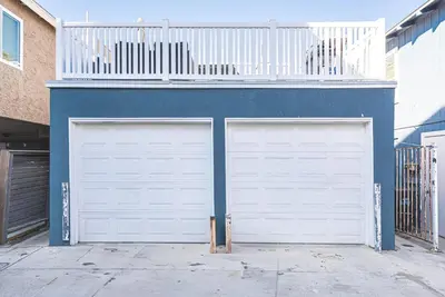 two garage doors in front of a blue building at Charming 3Br W Large Deck, Walk To Beach And Marina Park By Beachview Rentals in Newport Beach