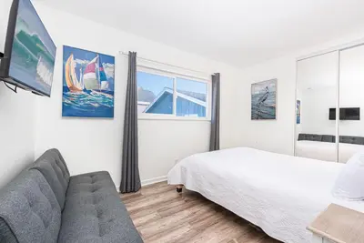 a white bedroom with a bed and a couch at Charming 3Br W Large Deck, Walk To Beach And Marina Park By Beachview Rentals in Newport Beach