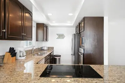 a kitchen with wooden cabinets and a black counter top at 5Br Coastal Retreat W Ocean Views - Steps From Beach By Beachview Rentals in Newport Beach