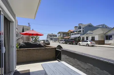 a balcony with an umbrella and a street with houses at 5Br Coastal Retreat W Ocean Views - Steps From Beach By Beachview Rentals in Newport Beach