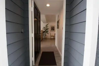 a hallway leading into a home with blue siding at 5Br Coastal Retreat W Ocean Views - Steps From Beach By Beachview Rentals in Newport Beach