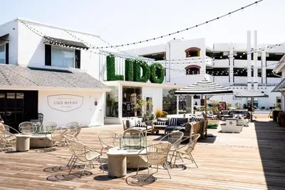 a patio with chairs and tables in front of a building at 5Br Coastal Retreat W Ocean Views - Steps From Beach By Beachview Rentals in Newport Beach