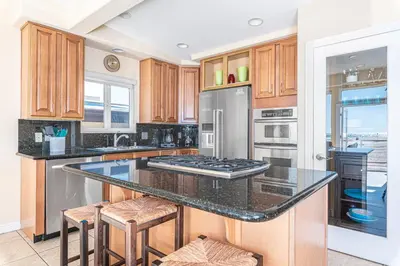 a kitchen with wooden cabinets and a granite counter top at 3Br Oceanfront W Panoramic Views In Prime Central Location By Beachview Rentals in Newport Beach