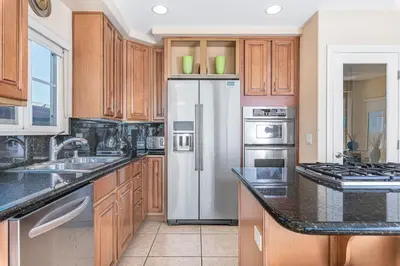 a kitchen with wooden cabinets and a stainless steel refrigerator at 3Br Oceanfront W Panoramic Views In Prime Central Location By Beachview Rentals in Newport Beach