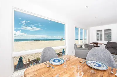 a dining room with a table and a view of the beach at Renovated 3Br Oceanfront W Panoramic Views By Beachview Rentals in Newport Beach